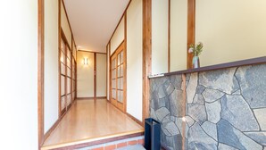 Un interior japonés tradicional con suelo de tatami, puertas correderas de madera y pared de piedra.
