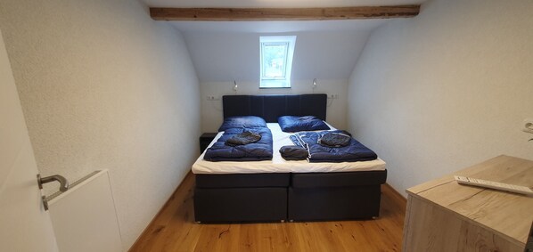 Un dormitorio pequeño y acogedor con una cama individual, una ventana y piso de madera.