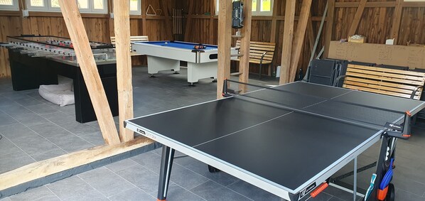 Une pièce équipée d’un baby-foot, d’une table de billard et d’une table de ping-pong.