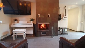 Een moderne woonkamer met een open haard, een flatscreen televisie en een gitaar.