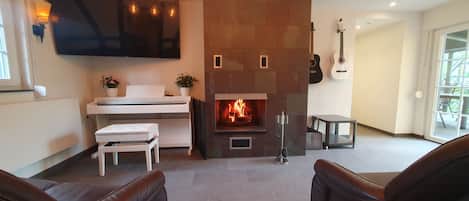 A modern living room with a fireplace, a flat-screen TV, and a guitar.