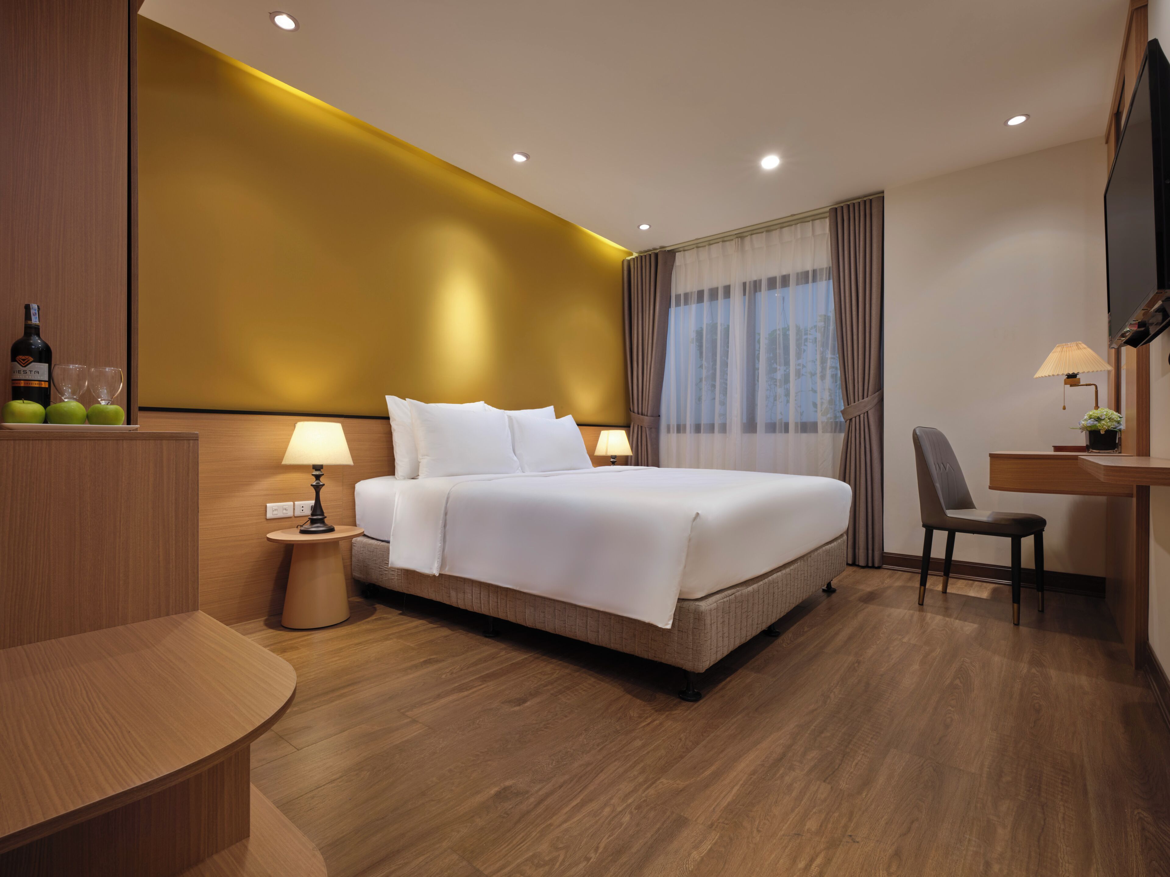 Ein modernes Hotelzimmer mit einem großen Bett, Nachttischen, einem Schreibtisch und einem Sessel.