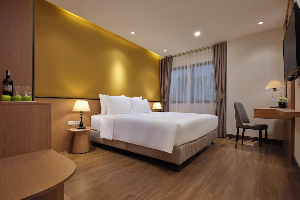 A modern hotel room with a large bed, bedside tables, a desk, and a chair.