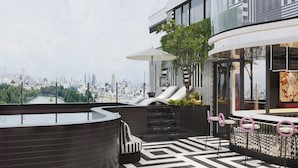 Una terraza moderna en la azotea con vistas panorámicas de la ciudad, un jacuzzi, asientos de descanso y una zona de bar.