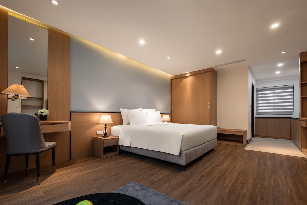 A modern hotel room with a bed, bedside tables, a desk, and a chair.