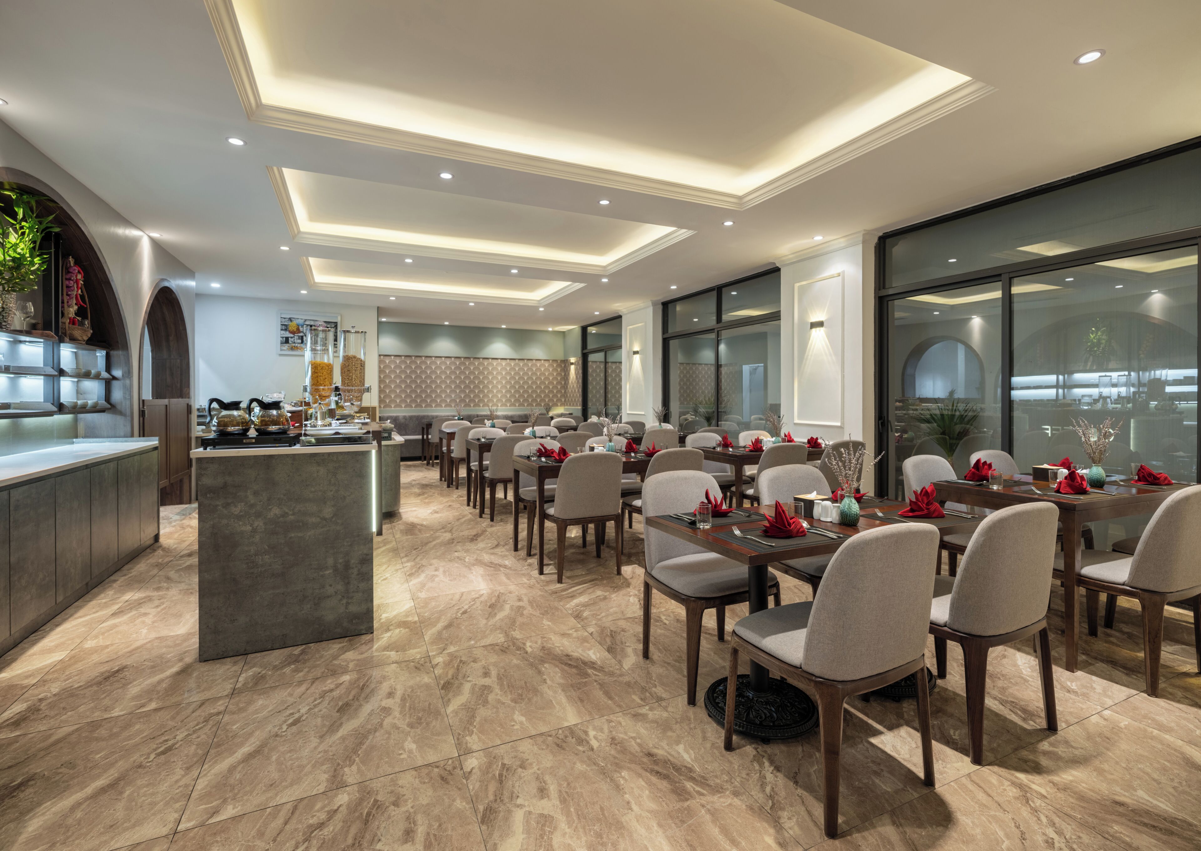 A modern dining area with a central island, multiple tables, and chairs, featuring a kitchen in the background.