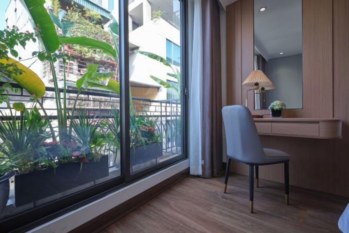 A room with a large window, a chair, a desk, and a lamp.
