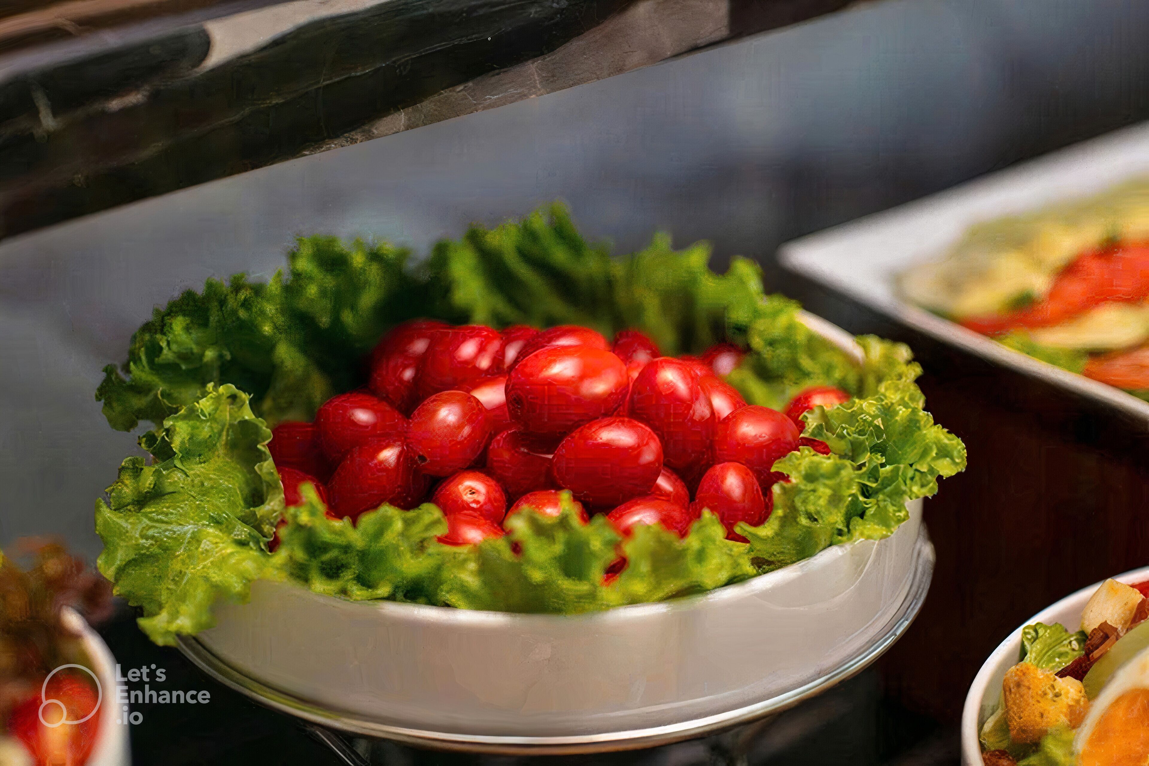 A salad bowl with cherry tomatoes and lettuce on a table.