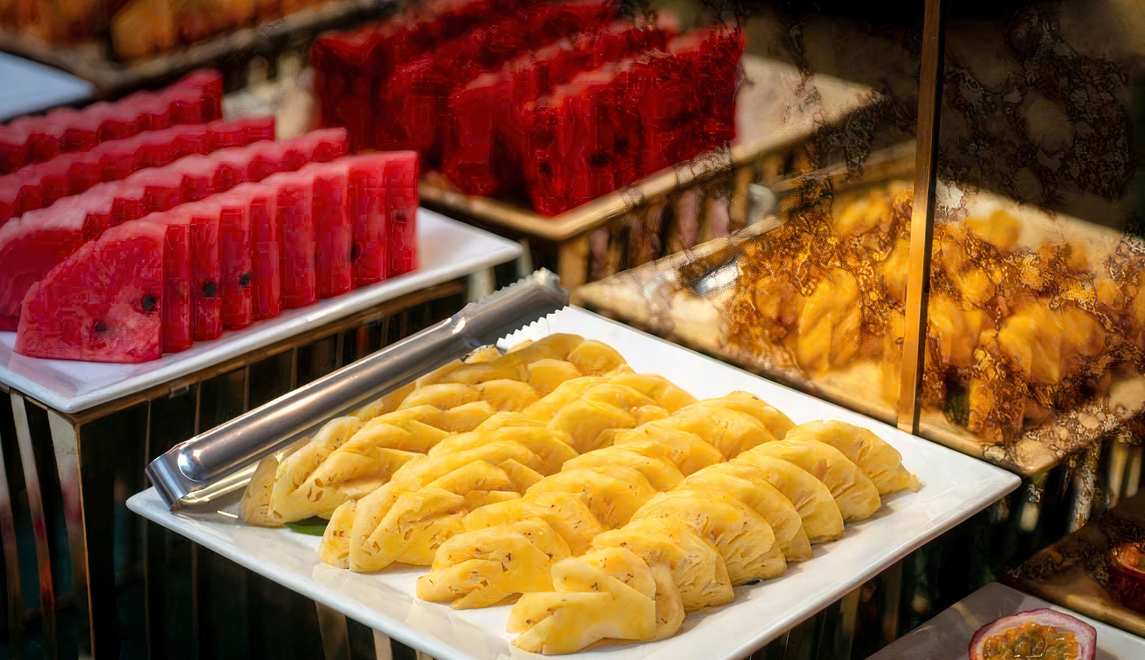 A buffet with various food items including watermelon, bread, and passion fruit.