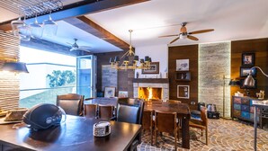 A modern kitchen with a fireplace, dining area, and large windows. - Villa Panorama (Crikvenica)