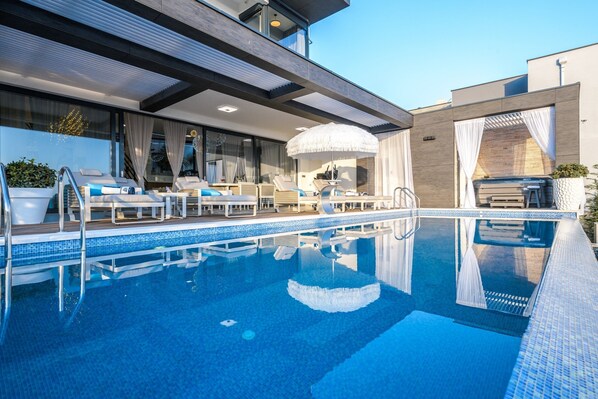 A modern outdoor pool area with lounge chairs and a hot tub. - Villa Panorama (Crikvenica)