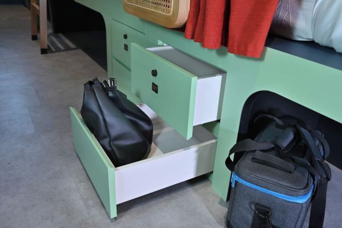 A green desk with a drawer containing a black bag and a grey bag.