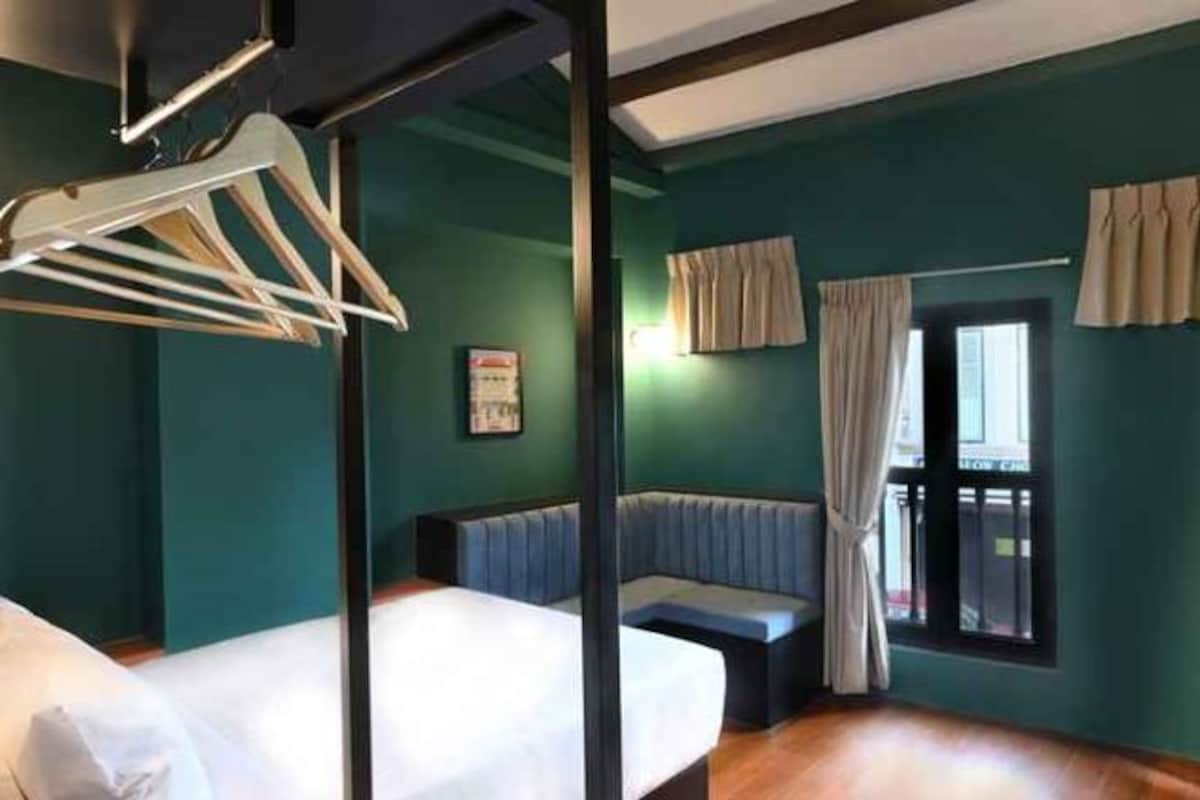 A room with a bed, a bench, and a window with curtains.