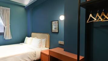 A bedroom with a bed, bedside tables, a hanging wardrobe, and a small stool.