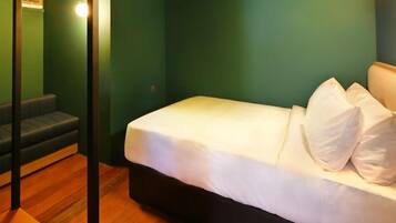 A room with a bed, a bench, and a wooden floor.