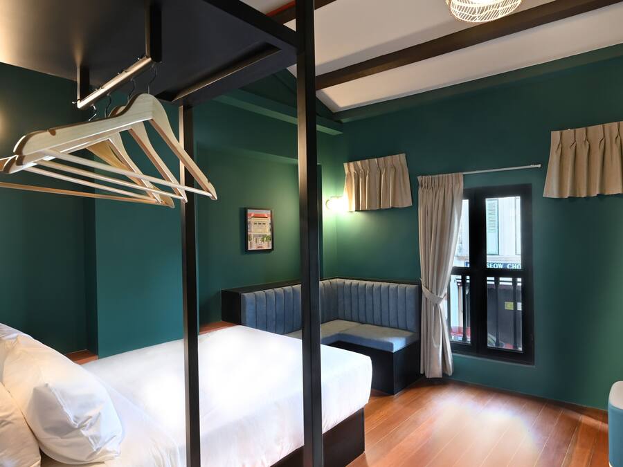 A modern bedroom with a bed, a bench, and a hanging light fixture.