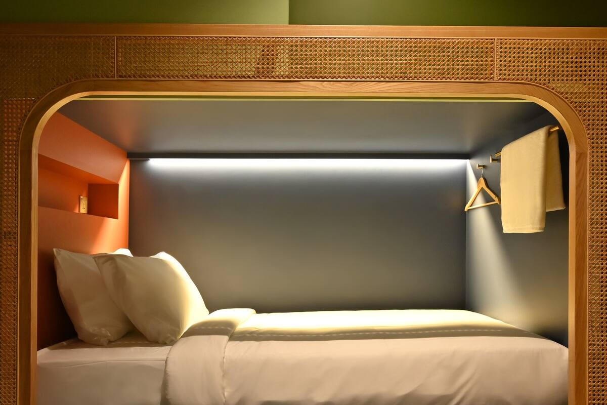 A bunk bed with a mattress, pillows, and a hanging towel.