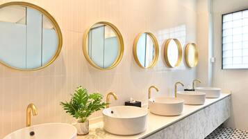 A modern bathroom with a long vanity, multiple sinks, and large mirrors.