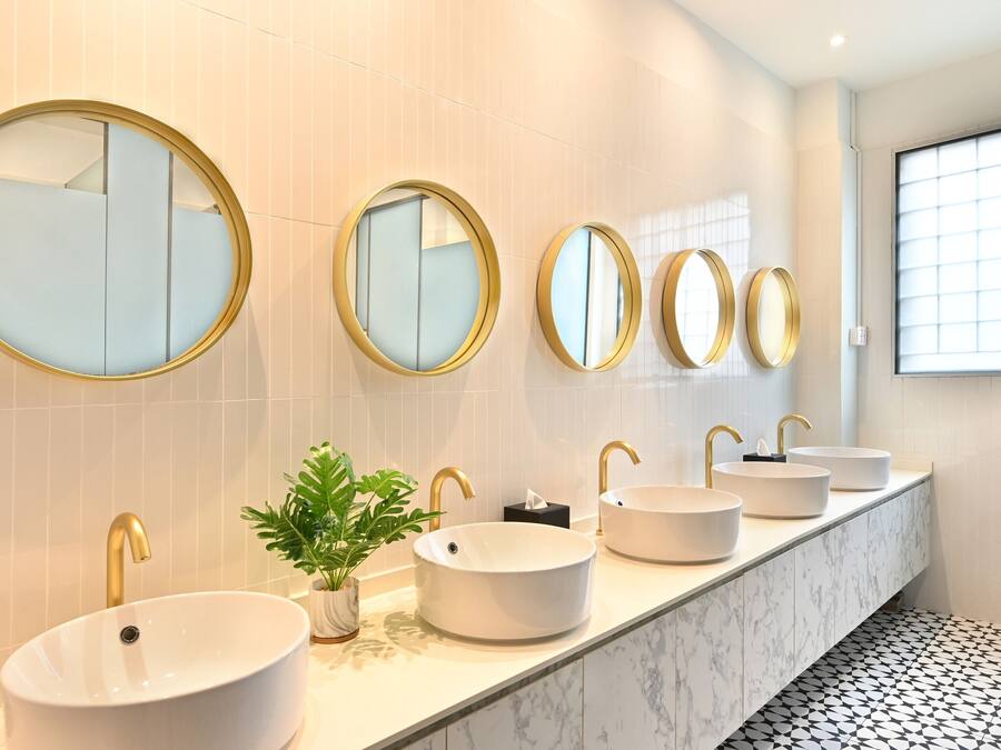 A modern bathroom with a long vanity, multiple sinks, and large mirrors.