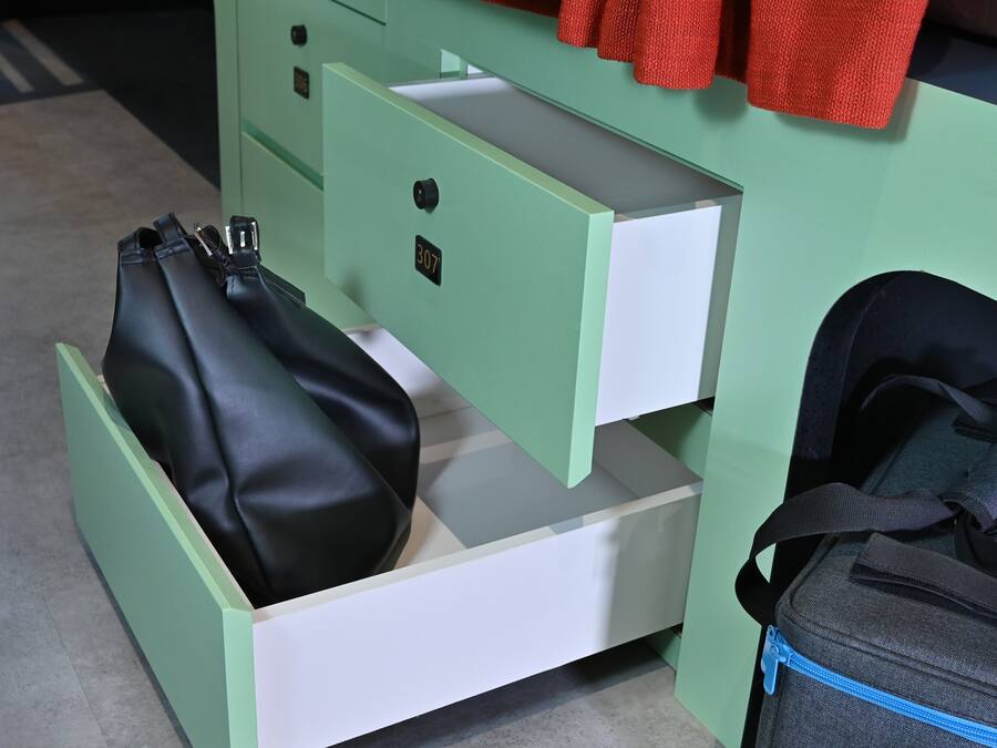 A green storage unit with a black bag and a gray bag inside.