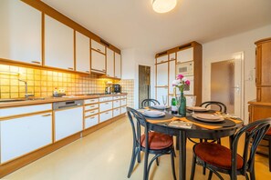A modern kitchen with white cabinets, a dishwasher, and a dining area with a table set for two.