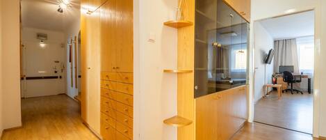 A modern interior with wooden cabinetry, a glass partition, and a visible office area with a desk and chair.