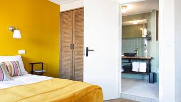 A bedroom with a bed, a wardrobe, and a bathroom visible through an open door.