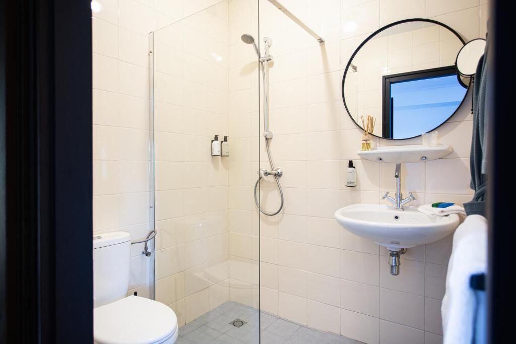A modern bathroom with a glass shower enclosure, a white toilet, and a sink with a mirror above it.