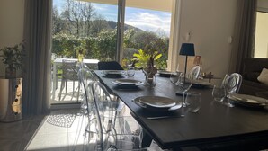 A dining area with a table set for four, large windows, and a view of greenery and hills. - Magnificent new villa between sea and mountains, between Porticcio and Ajaccio (cauro)