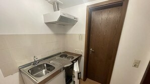 A compact kitchen with a sink, stove, and oven. - Beny Hotel Restaurant  (Bad Bellingen)