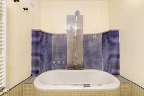 A bathroom with a bathtub, a shower, and blue-tiled walls. - Trastevere Hyperloft (Rome)
