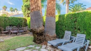 A patio area with stone flooring, two lounge chairs, and a small table. - Oliva Nova Golf Yellow House (OLIVA)