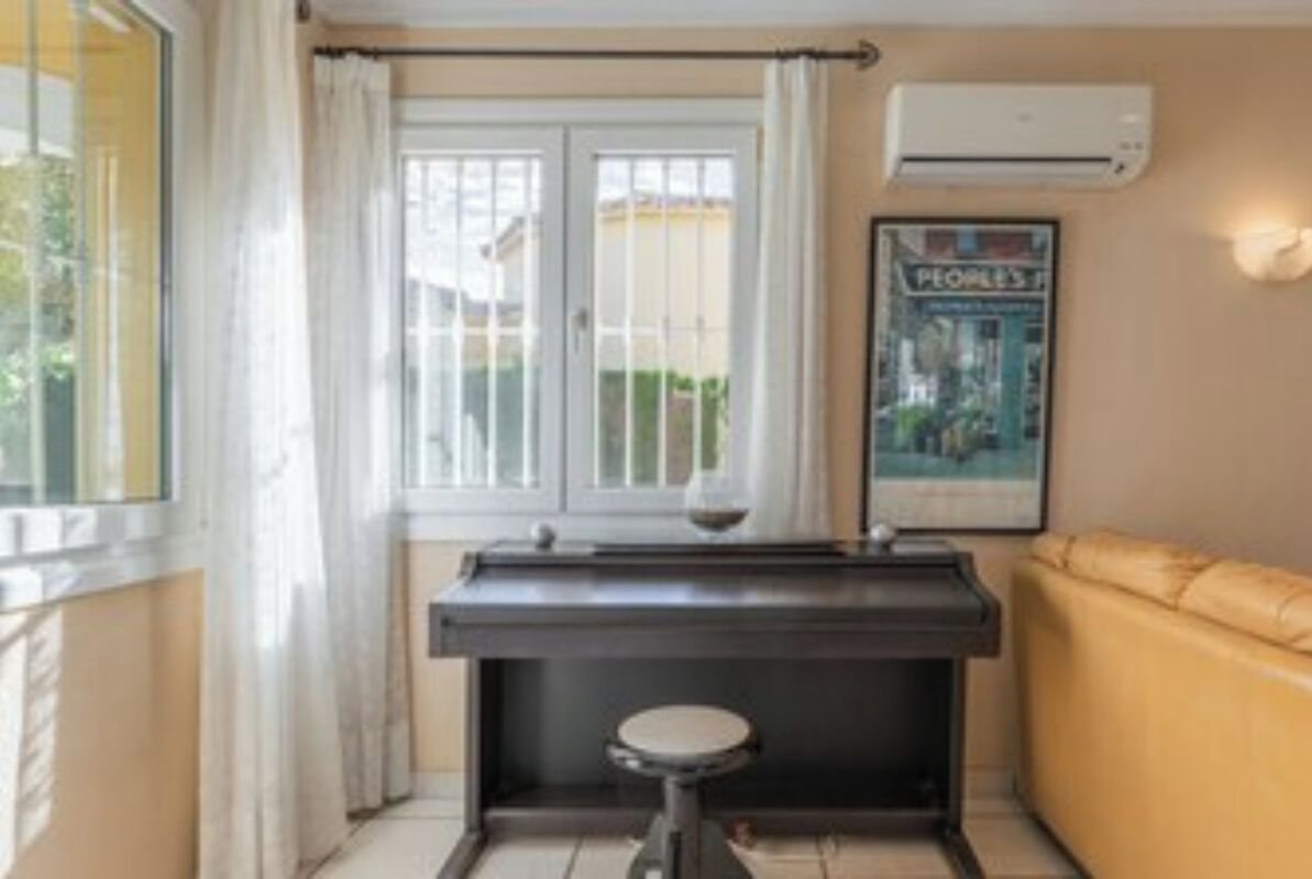 Une pièce avec une fenêtre, un petit tabouret, un canapé et un appareil de climatisation.