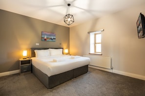 A bedroom with a large bed, bedside lamps, a painting on the wall, a window, and a ceiling light fixture. - Escape Ordinary at Castle Hume No.17 ~ 3 bedroom (Castle Hume/Lough Erne)
