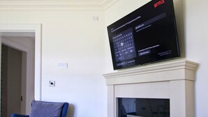 En platt-TV som är monterad på väggen ovanför en öppen spis och som visar Netflix användargränssnitt.