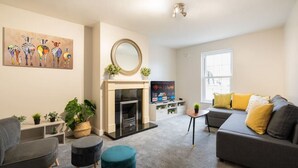 Una sala de estar moderna con chimenea, un sofá, un televisor y un cuadro en la pared.