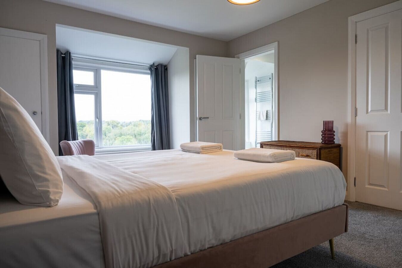 A bedroom with a large bed, a dresser, and a window with curtains.