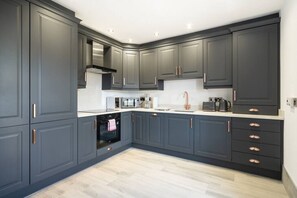 Una cocina moderna con armarios grises oscuros, electrodomésticos de acero inoxidable y una encimera de color claro.