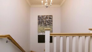 Un escalier avec des rampes blanches et un lustre.