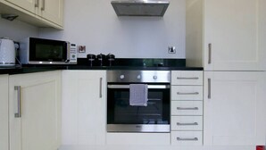 Une cuisine avec des armoires blanches, un four à micro-ondes, une cuisinière et une hotte aspirante.