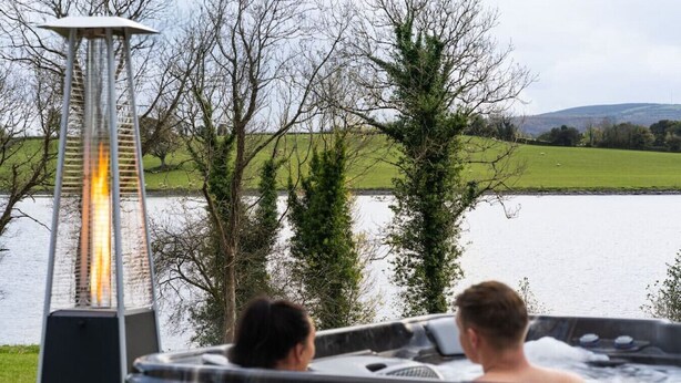 Una vasca idromassaggio con due persone, un lampione e vista sul lago.