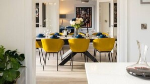 Una cucina moderna con un piano di lavoro bianco, sedie gialle e un'area pranzo con tavolo apparecchiato per quattro persone.
