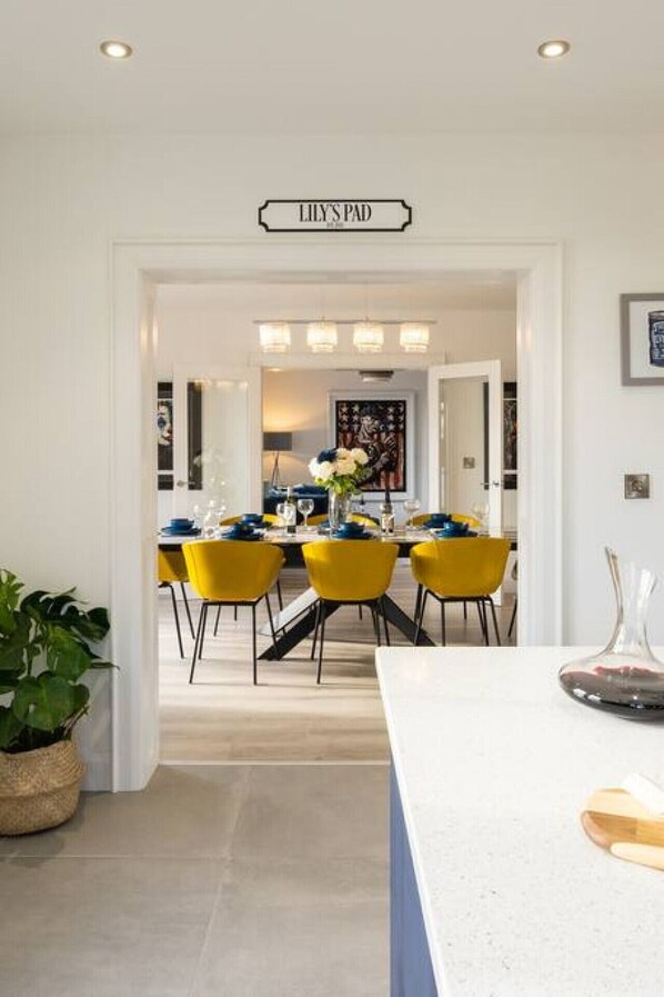 A modern kitchen with a white countertop, yellow chairs, and a dining area with a table set for four.