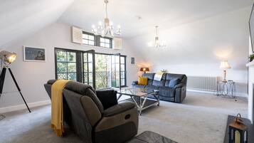 A spacious living room with a high ceiling, a sofa, a coffee table, and a fireplace.