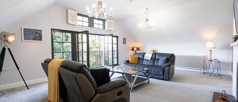 Un salon spacieux avec un plafond haut, un canapé, une table basse et une cheminée.