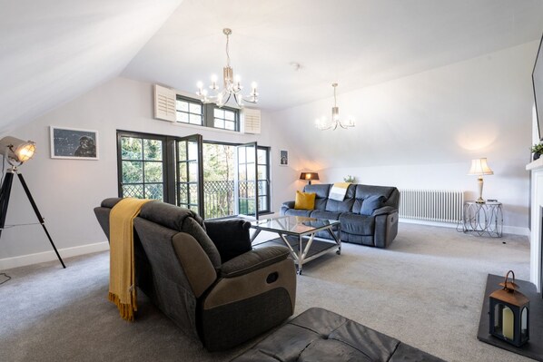 A spacious living room with a high ceiling, a sofa, a coffee table, and a fireplace.
