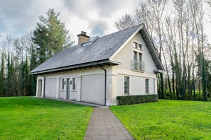 Une maison à deux étages avec un toit en pente, un garage et une allée pavée menant à l’entrée.