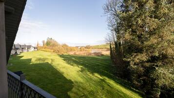 A well-maintained lawn with a view of a distant building and a tree-lined area.