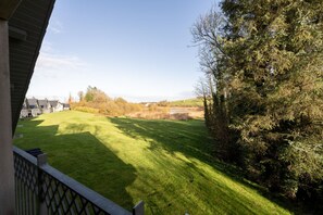 A well-maintained lawn with a view of a distant building and a tree-lined area.