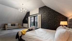 A bedroom with a large bed, a chandelier, a sofa, and a window with shutters. - 60 Lough Erne Golf Village · Escape Ordinary at Lough Erne! (Castle Hume/Lough Erne)